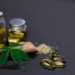 Assorted cannabis products including hemp seeds, oil, and capsules on dark background.
